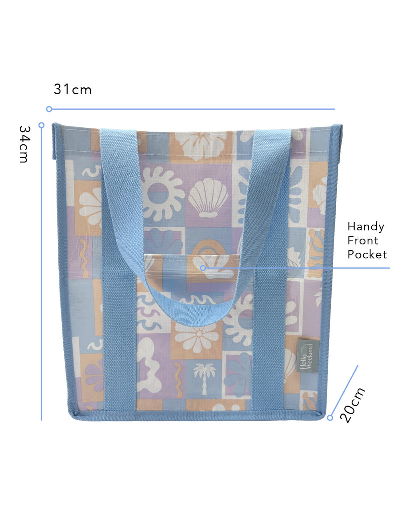 A square canvas tote bag with a pastel patchwork pattern featuring seashells, flowers, and palm trees in lavender, orange, and light blue, with solid light blue handles.  Lizzie Print - Daily Bag - Reusable bags online | Weekender bags | Shopper bags | Pouches  Hello Weekend Beige canvas handles | Beach Bags