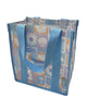 A square canvas tote bag with a pastel patchwork pattern featuring seashells, flowers, and palm trees in lavender, orange, and light blue, with solid light blue handles.  Lizzie Print - Daily Bag - Reusable bags online | Weekender bags | Shopper bags | Pouches  Hello Weekend Beige canvas handles | Beach Bags