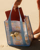 A square canvas tote bag with a pastel patchwork pattern featuring seashells, flowers, and palm trees in lavender, orange, and light blue, with solid light blue handles.  Lizzie Print - Daily Bag - Reusable bags online | Weekender bags | Shopper bags | Pouches  Hello Weekend Beige canvas handles | Beach Bags