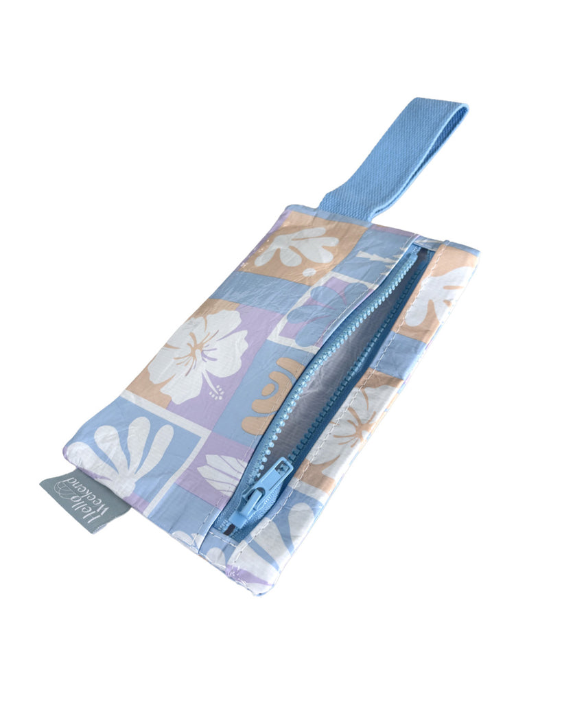 A small zippered pouch with a blue wrist strap, featuring a patchwork pattern of light blue, lavender, and peach squares with white floral and leaf motifs. A small fabric tag on the right reads Hello Weekend. Lizzie  Print - Phone Pouch - Reusable bags online | Daily bags | Shopper bags | Weekender bags  Hello Weekend