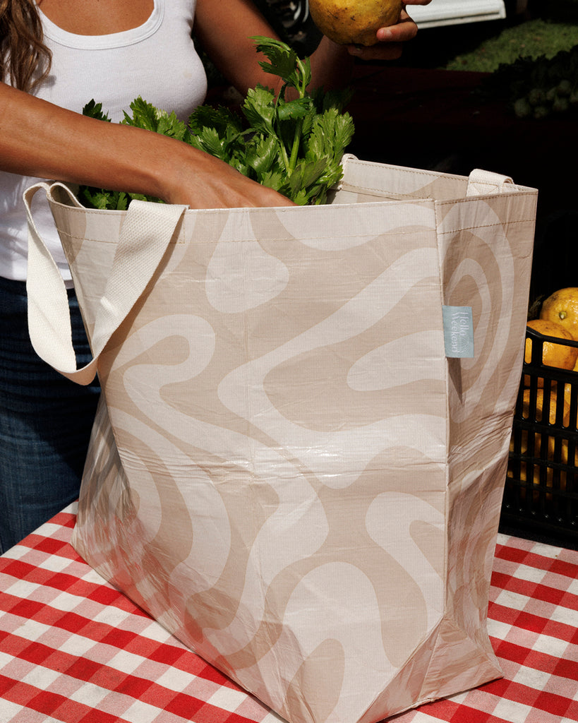 Beige tote bag with wavy pattern on a red and white checkered tablecloth. Sandy Print - Weekender Bag - Reusable bags online | Daily bags | Shopper bags | Pouches  Hello Weekend Beige canvas handles | Beach Bags
