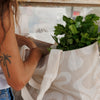 Person holding a reusable shopping bag with green leafy vegetables. Sandy Print - Weekender Bag - Reusable bags online | Daily bags | Shopper bags | Pouches  Hello Weekend Beige canvas handles | Beach Bags