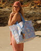 A Hello Weekend large bag with a pastel patchwork pattern featuring beach motifs like seashells, palm trees, and waves in lavender, blue, orange, and white, with light blue handles. Lizzie Print - Weekender Bag - Reusable bags online | Daily bags | Shopper bags | Pouches  Hello Weekend Beige canvas handles | Beach Bags