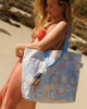 A Hello Weekend large bag with a pastel patchwork pattern featuring beach motifs like seashells, palm trees, and waves in lavender, blue, orange, and white, with light blue handles. Lizzie Print - Weekender Bag - Reusable bags online | Daily bags | Shopper bags | Pouches  Hello Weekend Beige canvas handles | Beach Bags